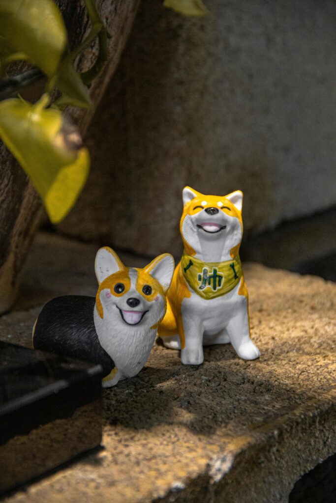 Two cute corgi figurines displayed on a decorative indoor shelf.